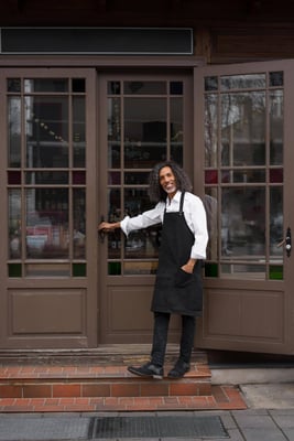 Baker standing at the entrance of a bakery, welcoming customers