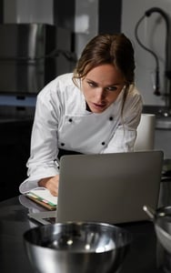 chef checking on the recipe management software for new dish