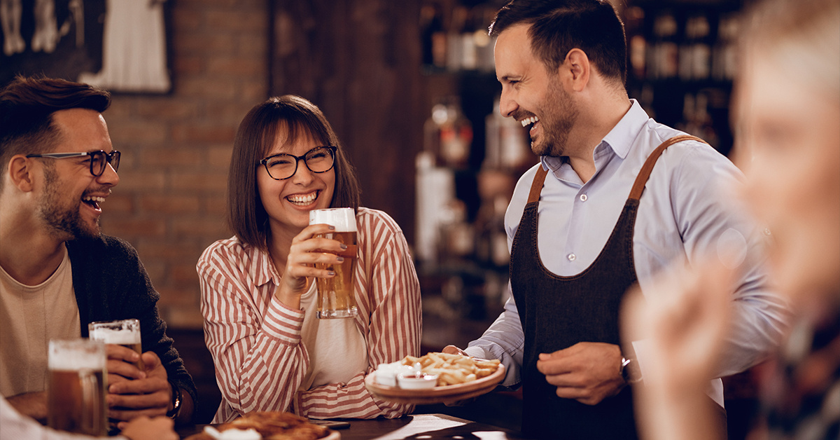 happy customers drinking beer having fun with waiter